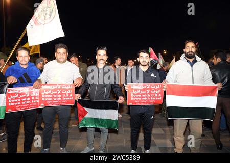 Bagdad, Irak. Januar 2024. Menschen mit Banner und Fahnen nehmen an einer Demonstration am 13. Januar 2024 auf dem Tahrir-Platz in Bagdad, Irak, Teil. Hunderte Iraker hielten am Samstag eine Kundgebung in der irakischen Hauptstadt Bagdad ab, um gegen die Angriffe der USA und Großbritanniens auf einige Militäreinrichtungen der Huthi im Jemen zu protestieren. Quelle: Khalil Dawood/Xinhua/Alamy Live News Stockfoto