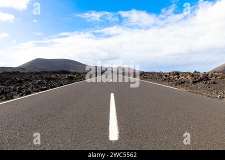 Panoramablick auf leere Asphaltstraße LZ-67 in vulkanischer Landschaft des Timanfaya Nationalparks, Lanzarote, Kanarische Inseln, Spanien, Europa Stockfoto