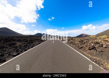 Panoramablick auf leere Asphaltstraße LZ-67 in vulkanischer Landschaft des Timanfaya Nationalparks, Lanzarote, Kanarische Inseln, Spanien, Europa Stockfoto