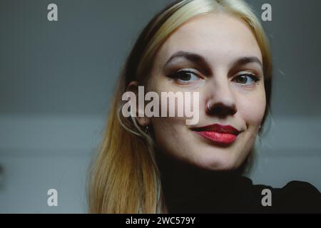 Eine detaillierte Nahaufnahme einer stilvollen Person, die Lippenstift aufträgt und gleichzeitig ein modernes Mobiltelefon hält Stockfoto
