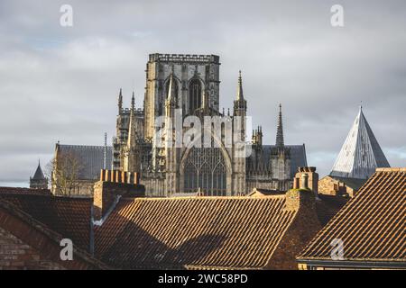 Blick auf das historische York Minster von den Dächern des Stadtzentrums von York, von den alten Stadtmauern aus gesehen. An einem bewölkten Tag mit Sonne. Stockfoto