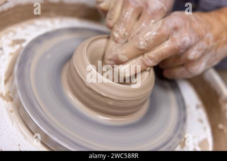 Männliche Hände machen Keramikbecher auf Töpferrad, Nahaufnahme Stockfoto