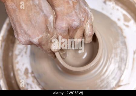 Männliche Hände machen Keramikbecher auf Keramikrad, Nahaufnahme, Draufsicht Stockfoto