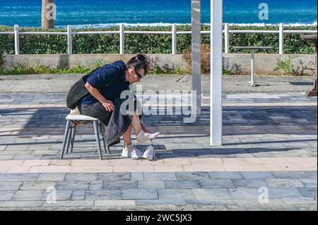 Frau zieht im Winter Turnschuhe auf dem Mittelmeer auf der Insel Zypern an Stockfoto