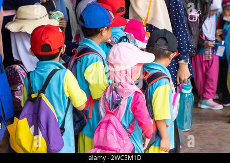 Kinder der Grundschule oder der Kindergärtnerschule besuchen einen Park mit Eltern und Lehrern in ihren traditionellen Trachten oder Kleidern in Kual Stockfoto