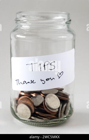 Ein Trinkgeldglas mit Geld und einem Etikett mit der Aufschrift „Tipps und Danke“. Stockfoto