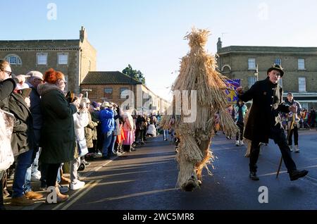 Der Strohbär wird während des Whittlesea Straw Bear Festivals in Whittlesea, Cambridgeshire, begleitet von Pflegern, Musikern und Tänzern durch die Straßen geführt. Bilddatum: Samstag, 13. Januar 2024. Stockfoto