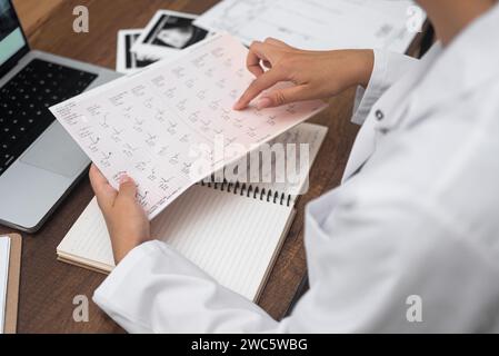 Arzt Kardiologe Hand Close Up untersucht Kardiogrammzeichnung sitzend am Tisch mit Computer Stockfoto