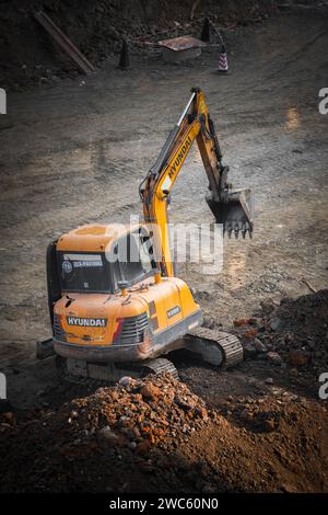 Der Bagger gräbt und transportiert am frühen Morgen Gegenstände Stockfoto