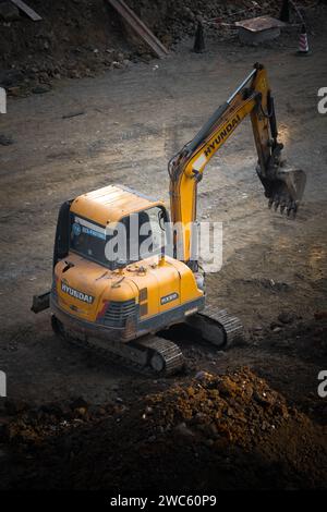 Der Bagger gräbt und transportiert am frühen Morgen Gegenstände Stockfoto