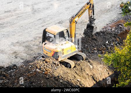 Der Bagger gräbt und transportiert am frühen Morgen Gegenstände Stockfoto