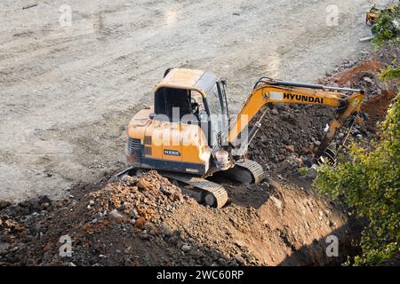 Der Bagger gräbt und transportiert am frühen Morgen Gegenstände Stockfoto