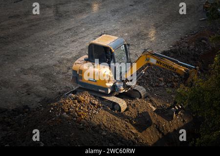 Der Bagger gräbt und transportiert am frühen Morgen Gegenstände Stockfoto