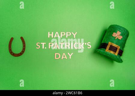 Horizontales Banner mit Happy St. Patrick-Schriftzug auf grünem isoliertem Hintergrund mit grünem Leprechaun-Hut mit goldenem Schamrock, Glückshufeisen. Tradi Stockfoto
