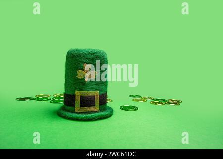 Grüner Leprechaun-Hut aus Filz, verziert mit Schamrock und verstreuten Goldmünzen auf isoliertem Hintergrund Stockfoto