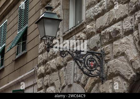 Alte Straßenlaterne an einer Hauswand mit dem Stadtwappen, Genua, Italien Stockfoto