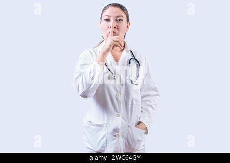 Eine Ärztin, die die schweigende Geste isoliert. Schöne Ärztin, die zum Schweigen kommt und in die Kamera schaut Stockfoto