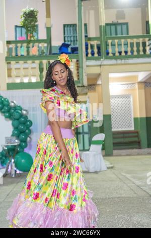 Elegante Tänzerin in einem floralen Cumbia-Rock mit einer hellen Haarblume bei einer kulturellen Feier. Stockfoto
