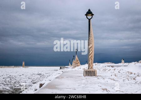 Lake Erie Pier in Ontario, Kanada, Lichtmasten mit Eis bedeckt. Natürliche Eisskulpturen, die aus Wellen während eines Wintersturms entstanden sind Stockfoto