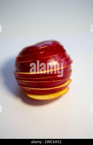 Glänzender roter Apfel mit herausgeschnittenen Scheiben. Wieder in Form des Apfels zusammensetzen. Stockfoto