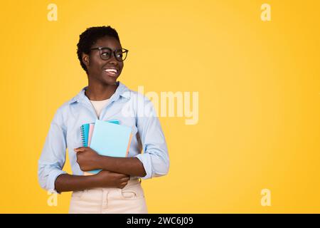 Gute schwarze junge Studentin in Brille, mit Büchern, schau dir den Kopierraum an Stockfoto