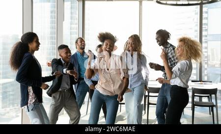 Überfreudige Gruppe multikultureller Studenten, die in modernen Büros tanzen Stockfoto