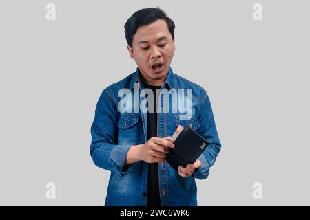 Junger asiatischer Mann mit aufgeregtem Gesichtsausdruck, während er seine Brieftasche hält und das Geld zählt Stockfoto