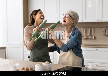 Fröhliche Mutter und aufgeregte Erwachsene Tochter, die Spaß in der Küche haben Stockfoto