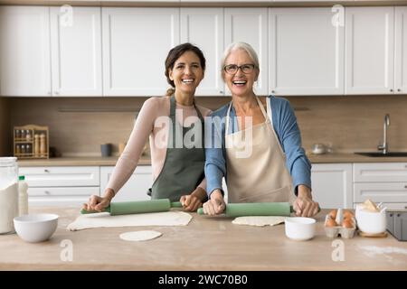 Fröhliche jüngere und ältere Bäckerinnen, die hausgemachte Backwaren kochen Stockfoto