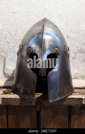 Der eiserne Helm des mittelalterlichen Ritters steht auf einem Holzregal Stockfoto