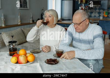Ein älterer Mann und eine ältere Frau sitzen an einem Tisch, trinken Tee und reden. Stockfoto