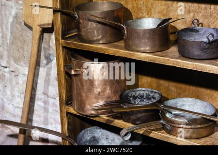 Alte Kupferpfannen stehen auf Holzregalen Stockfoto