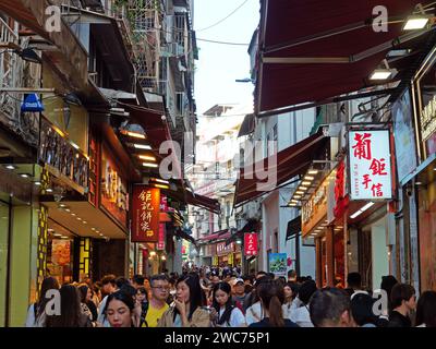 Eine typische geschäftige enge Straße in Macau, die mit Menschen, Geschäften, Bars und Restaurants überfüllt ist Stockfoto