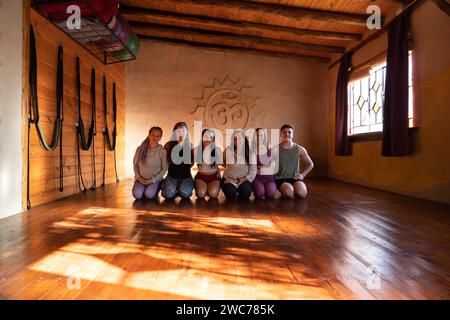 Gruppenporträt einer Gemeinschaft von Menschen, die Yoga praktizieren, lächeln und in die Kamera schauen. Allgemeine Aufnahme beleuchtet mit natürlichem Licht Stockfoto