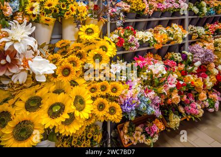 Gefälschte, mehrfarbige Blumen, Sonnenblumen und andere Arten von künstlichen Blumen, die auf dem Regal des Blumenhandels ausgestellt werden Stockfoto