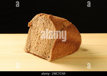 Stück traditionelles Brot auf Holzbrett auf dunklem Hintergrund Stockfoto