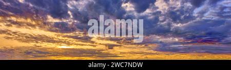 Der Himmel nach einem Sturm. Reich an wirbelnden Wolken und Flecken aus Blau, tiefem Violett, feurigen Orangen und sanften Gelbtönen. Stockfoto