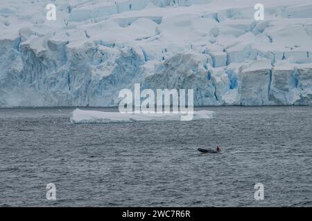 Zodiac-Erkundung der Bucht von Brialmont, antarktis an einem bewölkten Tag im Frühling, III. Und schneebedeckte Küste mit Eisbögen und Höhlen Stockfoto