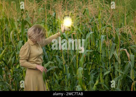 Junge Frau in gelbgoldenem Kleid vor dem Hintergrund des Maisfeldes im Sommer. Außenporträt einer jungen Frau in seliger Kleidung im Garten. Stockfoto