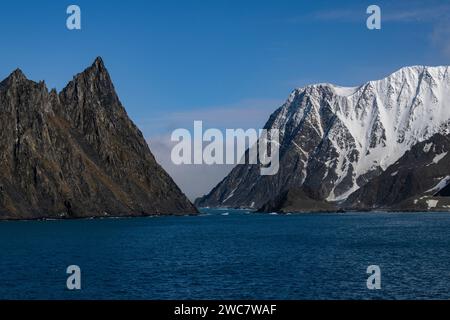 Elephant Island felsiges Ufer und hohe schneebedeckte Gipfel, Sternzeichen nähern sich der Küste, Rowett Island und Cape Lookout, steil aufragende Klippen aus dem Ozean Stockfoto