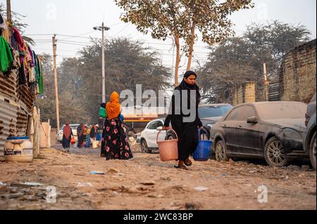 Neu-Delhi, Indien. Januar 2024. Eine Rohingya-Flüchtlingsfrau geht zurück nach Hause und transportiert Trinkwasser in einem Plastikbehälter, der von einem Verteilungsort im Flüchtlingslager Madanpur Khadar Rohingya geholt wurde. 1.100 Rohingyas, die in den Lagern von Madanpur Khadar leben, sind von der kommunalen Wasserversorgung abhängig. (Credit Image: © Pradeep Gaur/SOPA Images via ZUMA Press Wire) NUR REDAKTIONELLE VERWENDUNG! Nicht für kommerzielle ZWECKE! Stockfoto