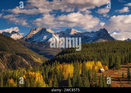 Bergbauhütte, eingebettet in Aspen- und Kiefernwälder unter schneebedeckten Bergen entlang des Million Dollar Highway in Colorado Stockfoto