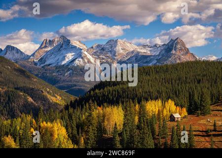 Bergbauhütte, eingebettet in Aspen- und Kiefernwälder unter schneebedeckten Bergen entlang des Million Dollar Highway in Colorado Stockfoto