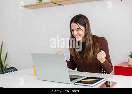 Eine begeisterte junge Geschäftsfrau, die sich glücklich fühlt, nachdem sie gute Nachrichten per E-Mail erhalten hat. Stockfoto