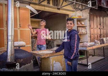 Die palästinensischen Jungs machen Brot in der örtlichen Bäckerei in der Innenstadt von Hebron, Westjordanland, Palästina. Stockfoto