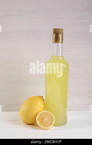 Flasche leckerer Limoncello-Likör und Zitronen auf weißem Holztisch Stockfoto