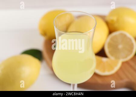 Likörglas mit leckerem Limoncello vor verschwommenem Hintergrund, Nahaufnahme Stockfoto