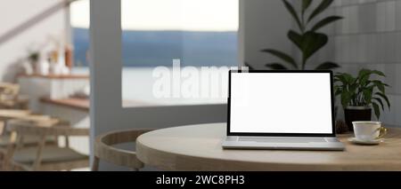 Ein Laptop-Mockup mit weißem Bildschirm und eine Kaffeetasse auf einem Tisch in einem wunderschönen modernen Café. Nahaufnahme. 3D-Rendering, 3D-Abbildung Stockfoto