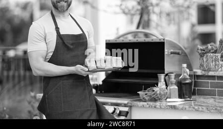 Grillen Sie Lachsfisch beim Mann tragen Sie eine Schürze mit Aussicht Stockfoto