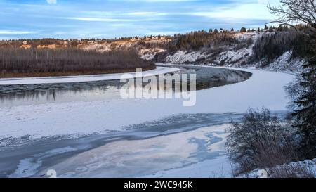 Terwillegar Park mit Blick auf die Fußbrücke zum North Saskatchewan River, der sich im frühen Winter mit gefrorenem Flusswasser entlang des Flussufers begibt Stockfoto